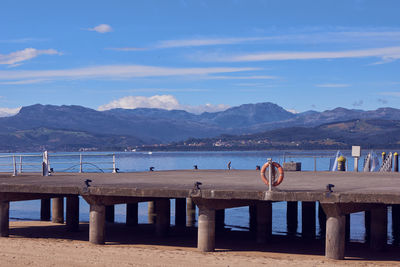 Scenic view of beach by mountains against sky