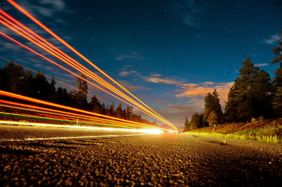 Light trails on road against sky at night