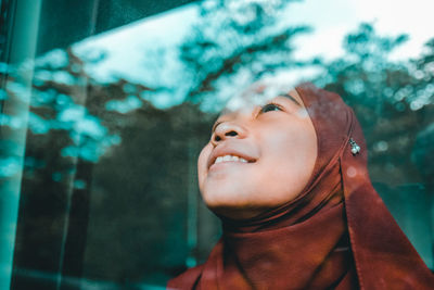 Smiling young woman wearing hijab seen through window