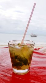 Close-up of drink on beach against sky