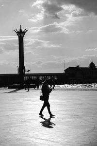 Silhouette man standing on water against cloudy sky