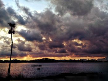 Scenic view of lake against dramatic sky during sunset