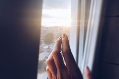 Cropped hand of woman touching glass window