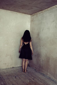 Rear view of woman standing against wall