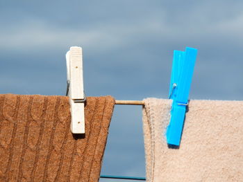 Low angle view of clothespins on clothesline against blue sky