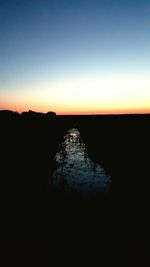 Silhouette of trees against clear sky at sunset