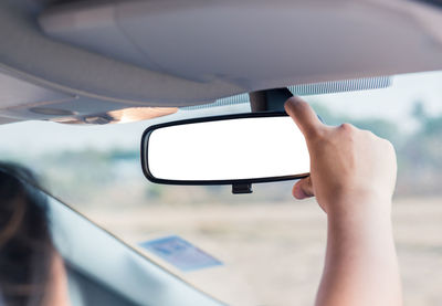 Close-up of hand holding rear-view mirror in car