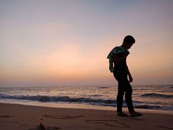 Full length of man standing on beach during sunset