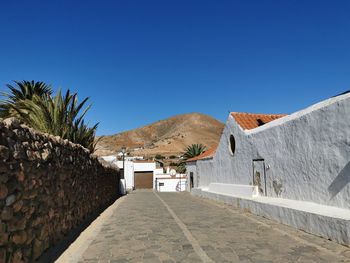 Houses on field against clear blue sky