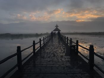 Pier over sea against sky during sunset