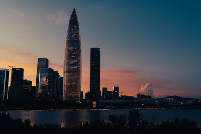 Illuminated buildings in city against sky during sunset