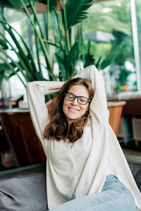 Portrait of young woman standing against plants