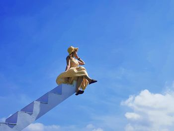 Low angle view of a girl against blue sky