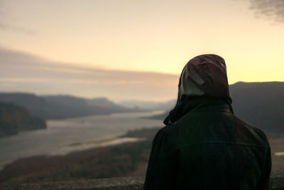 Rear view of man standing against sky during sunset