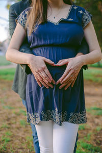 Midsection of woman holding umbrella standing on field