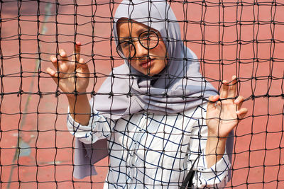 Asian muslim woman, wearing headscarf and glasses taking photo on tennis ball court