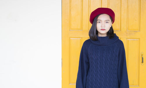 Portrait of woman standing against yellow wall