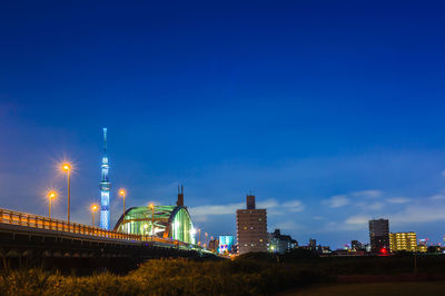 Low angle view of illuminated bridge against blue sky at night