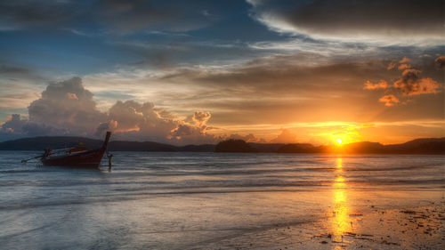 Lone boat in calm sea against sunset