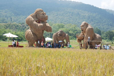 People by sculptures on field