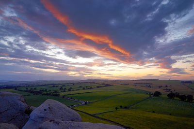 Scenic view of landscape against dramatic sky during sunset