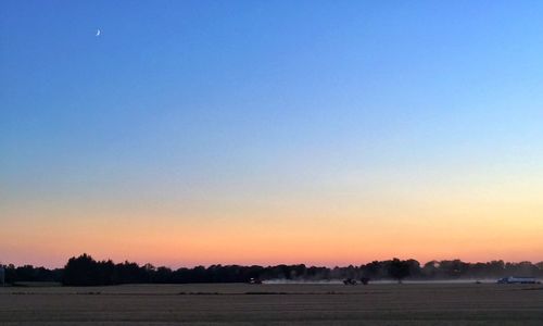 Scenic view of landscape against clear sky at sunset