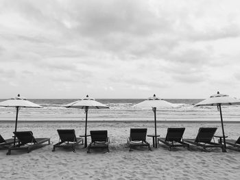 Chairs and tables on beach against sky