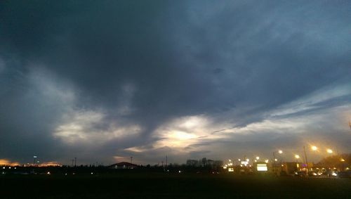 View of illuminated cityscape against cloudy sky