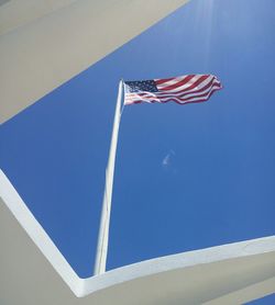 Low angle view of american flag against sky seen through roof