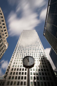 Low angle view of clock against modern buildings in city