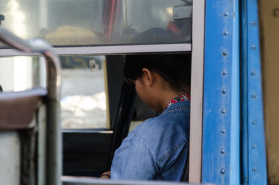 Side view of woman sitting in bus seen through window