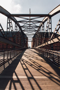 Metallic footbridge against sky during sunny day