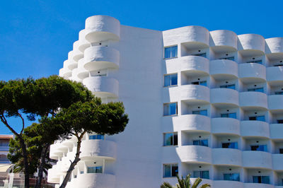 Low angle view of white hotel building against blue sky, cala d'or 