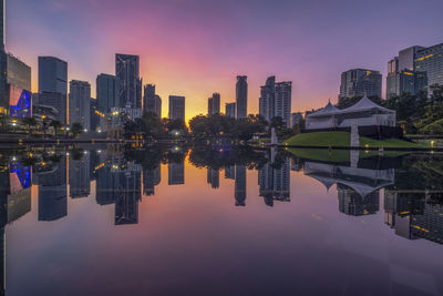 Reflection of buildings in city at sunset