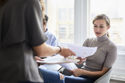 Female colleagues discussing documents in creative office