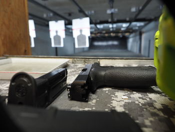 Closeup of pistol at gun range with targets blurred in background.