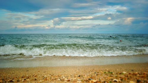 View of calm beach against cloudy sky