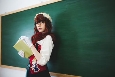 Portrait of a smiling young woman standing against the wall