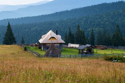 Built structure on field against trees and mountains