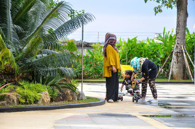 Rear view of man walking on palm trees against sky