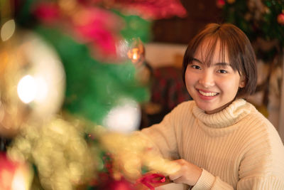 Portrait of smiling woman by christmas tree at home