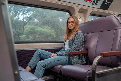Full length of woman sitting in train