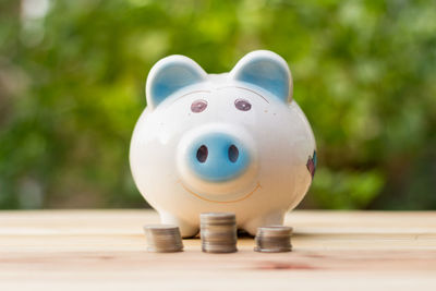 Close up of piggy bank with coins on wooden table