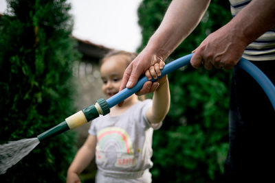 Little girl watering garden with her grandfather.