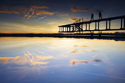 Pier in sea at sunset