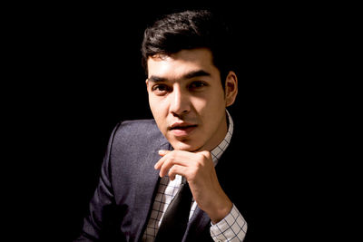 Portrait of young businessman against black background