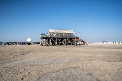 Lifeguard hut on beach against clear blue sky