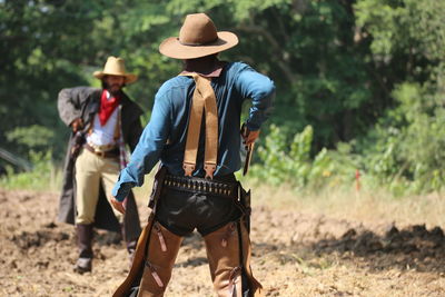 Men in costumes holding guns while standing against trees 