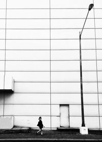 Man walking on cable against building