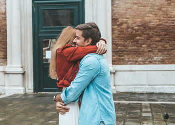 Rear view of man and woman standing against brick wall